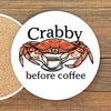 A white coaster with a red crab and a cup of coffee, accompanied by the text "Crabby before coffee".