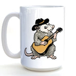 A white ceramic mug with a cartoon image of a furry opossum playing a guitar.
