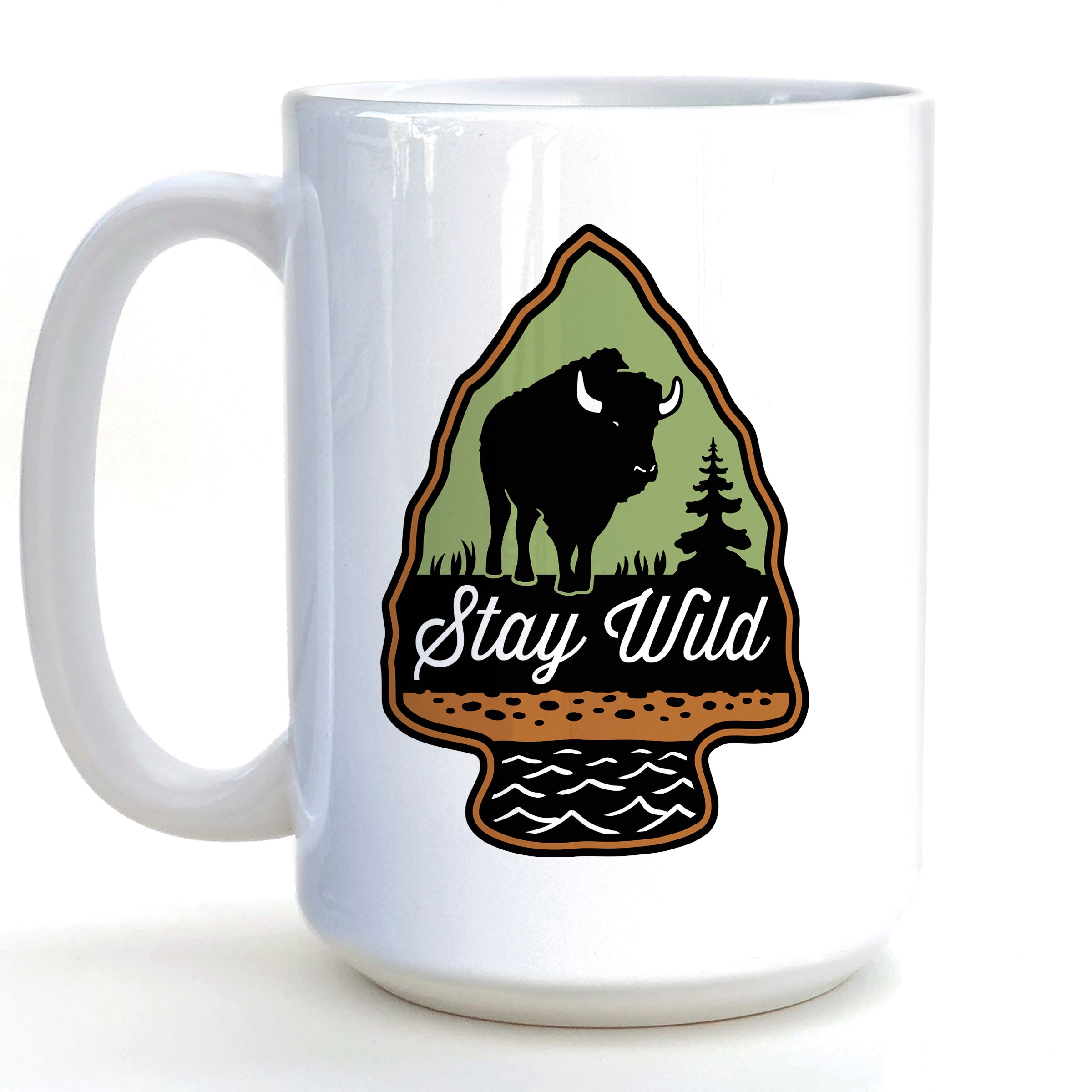 A white ceramic mug with a graphic design featuring a bison silhouette and the text "Stay Wild" inside an arrow-shaped emblem.