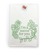 A white towel with a green graphic design featuring a wreath of succulent plants and the text "I'm a succa for you" printed on it.