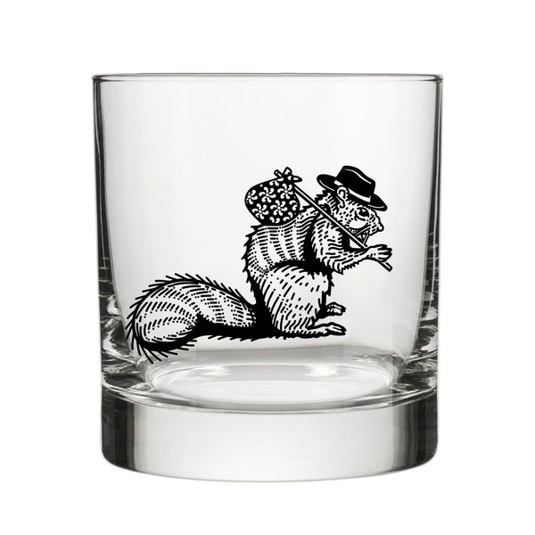Close-up of a unique whiskey glass featuring a hobo squirrel illustration. The glass is clear and showcases the detailed design perfectly against a white background.