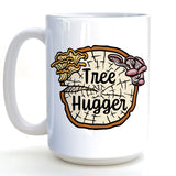 A white ceramic mug with a tree stump design and the text "Hugs" printed on it.