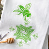 Unique tea towel design featuring a hand-illustrated green bee hovering over floral patterns, perfect for adding charm to your kitchen.