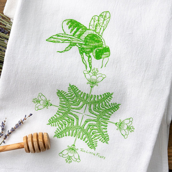 Unique tea towel design featuring a hand-illustrated green bee hovering over floral patterns, perfect for adding charm to your kitchen.