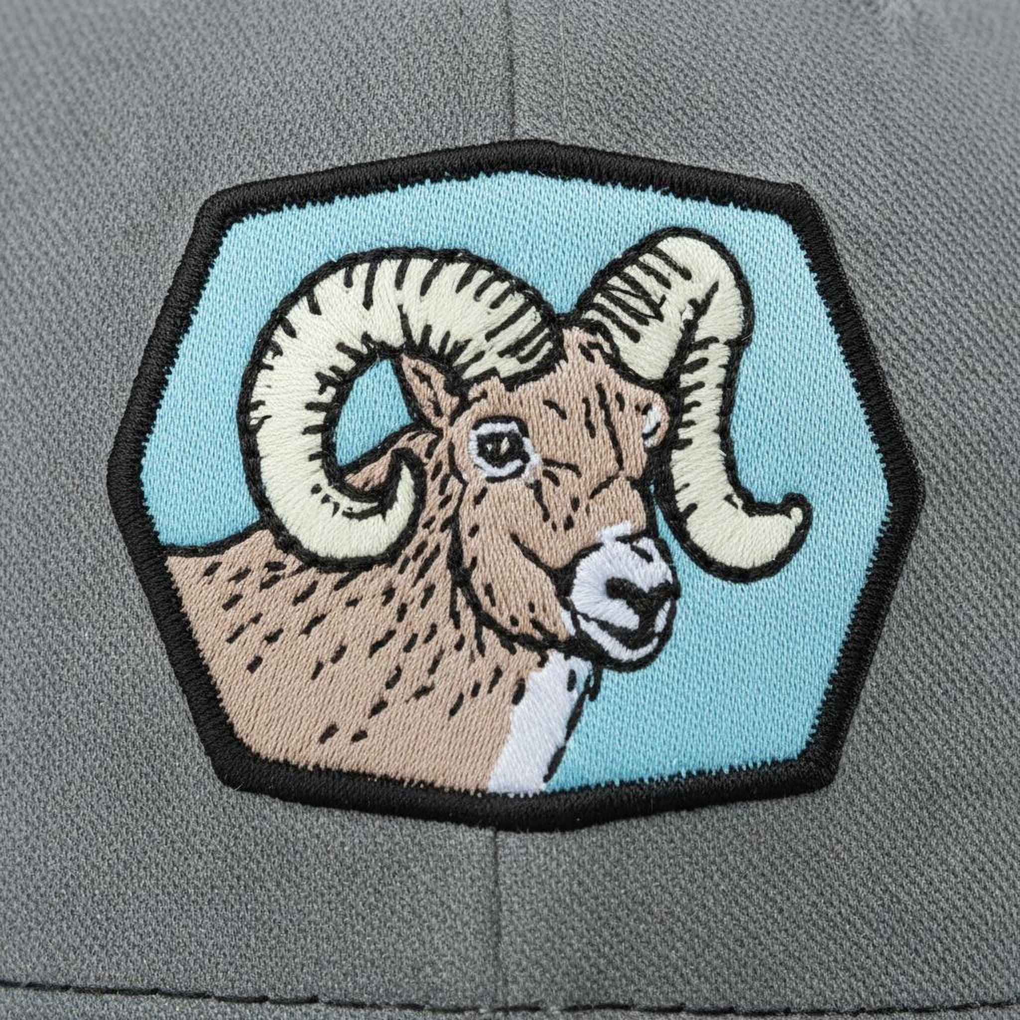 A close-up of a gray fabric with a patch featuring a cartoon image of a ram with large curved horns.