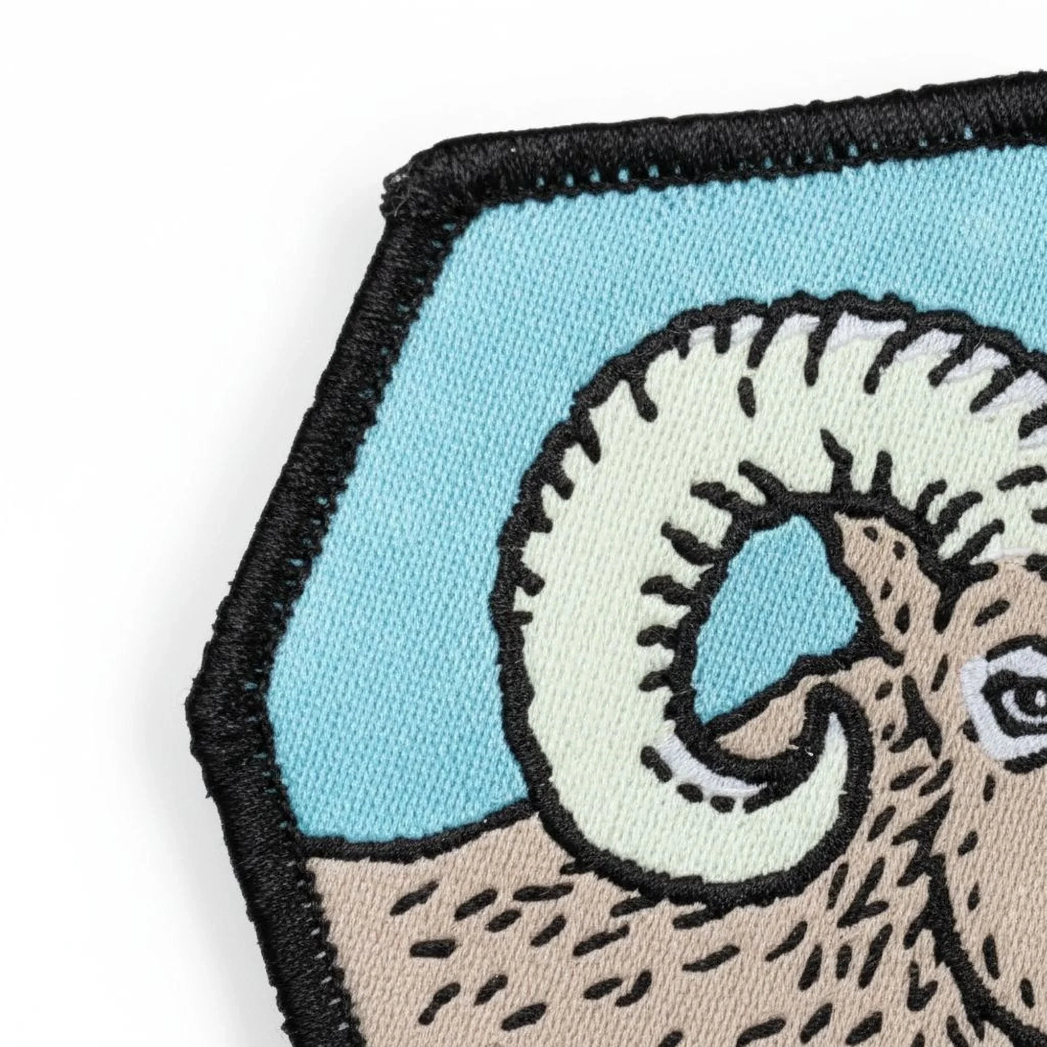 a close-up view of a patch with a detailed illustration of a ram's head, including its curved horns and distinctive facial features.