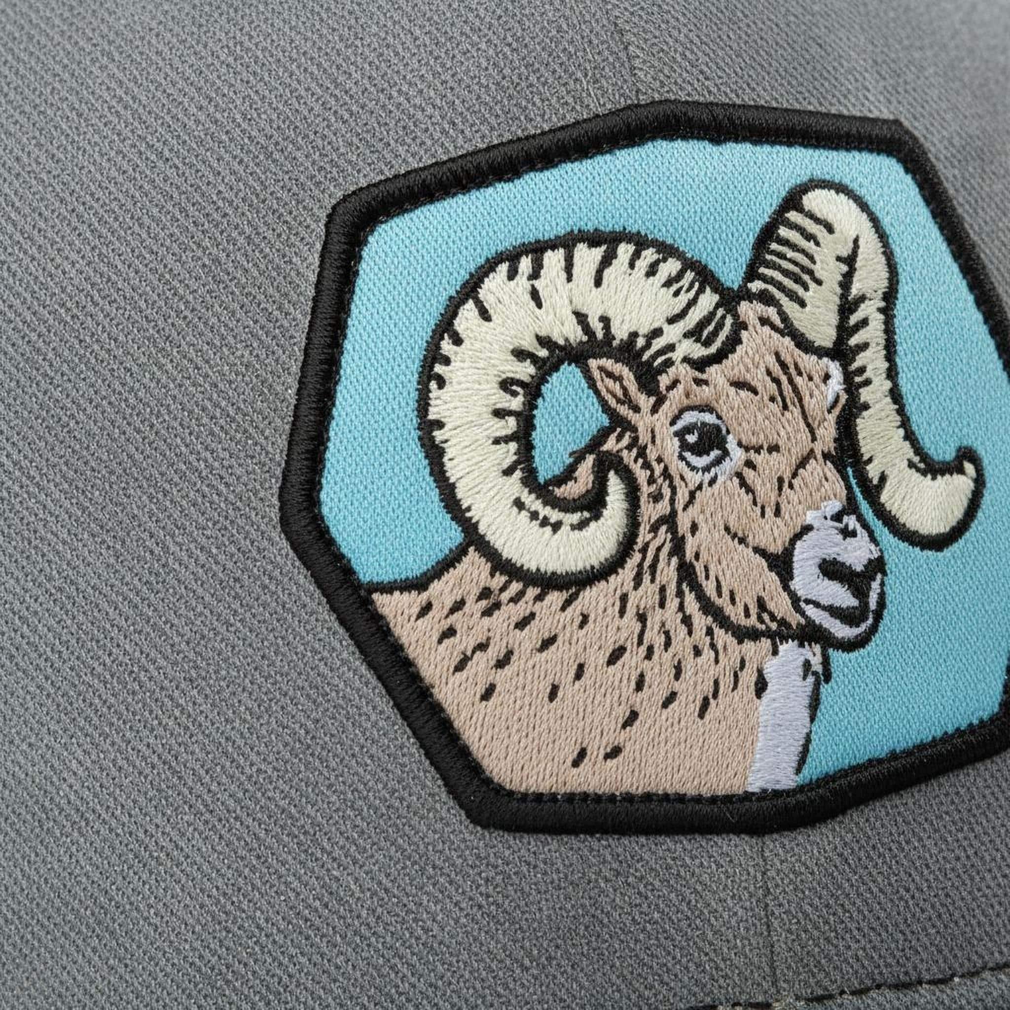 A close-up of a gray fabric with a patch featuring a detailed embroidered image of a ram's head.