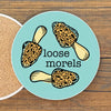 A round coaster with a cartoon image of leopard-print mushrooms and the text "Loose Morels" on it.