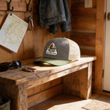 a wooden bench with a green and gray baseball cap resting on it, along with sunglasses and keys.