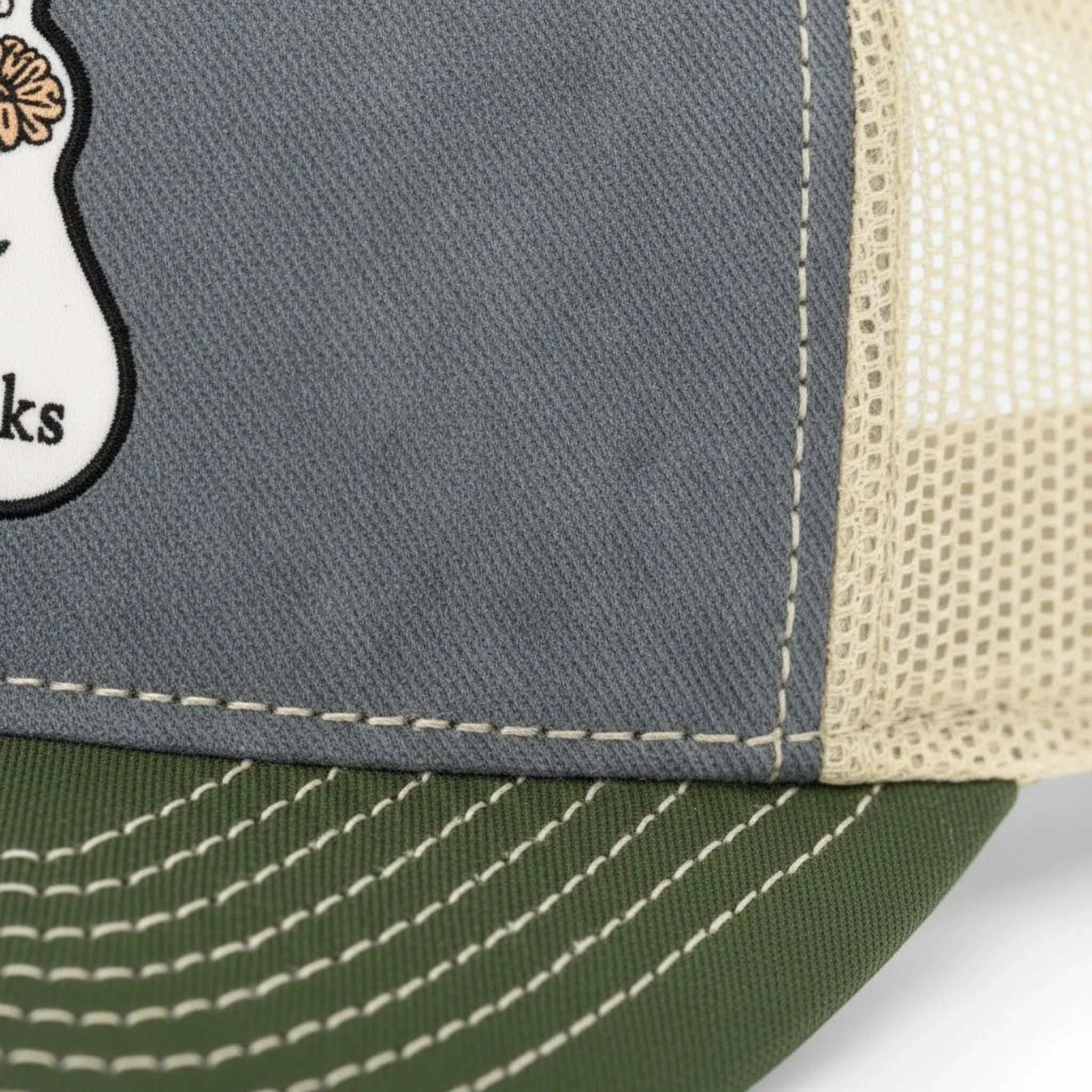A close-up view of a gray fabric with a white mesh panel on the side, showing the stitching and texture of the material.