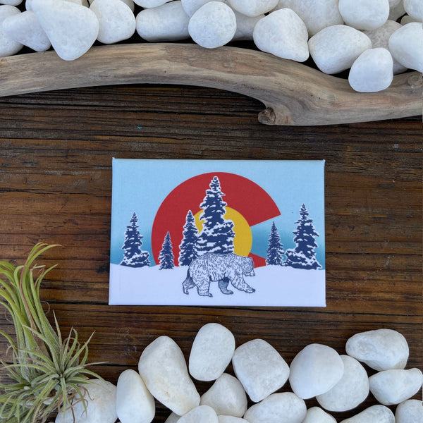 Cheerful Colorado Bear Fridge Magnet featuring snowy trees and the Colorado flag design. Perfect for adding personality to your kitchen and showcasing your love for the state.
