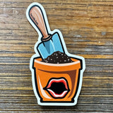 Cute Decorative Plant Stickers - Durable Terra Cotta Pot & Shovel Design, Weatherproof Vinyl Decal featuring an illustration of a terra cotta pot filled with soil and a shiny shovel, perfect for adding a whimsical touch to your gardening decor.