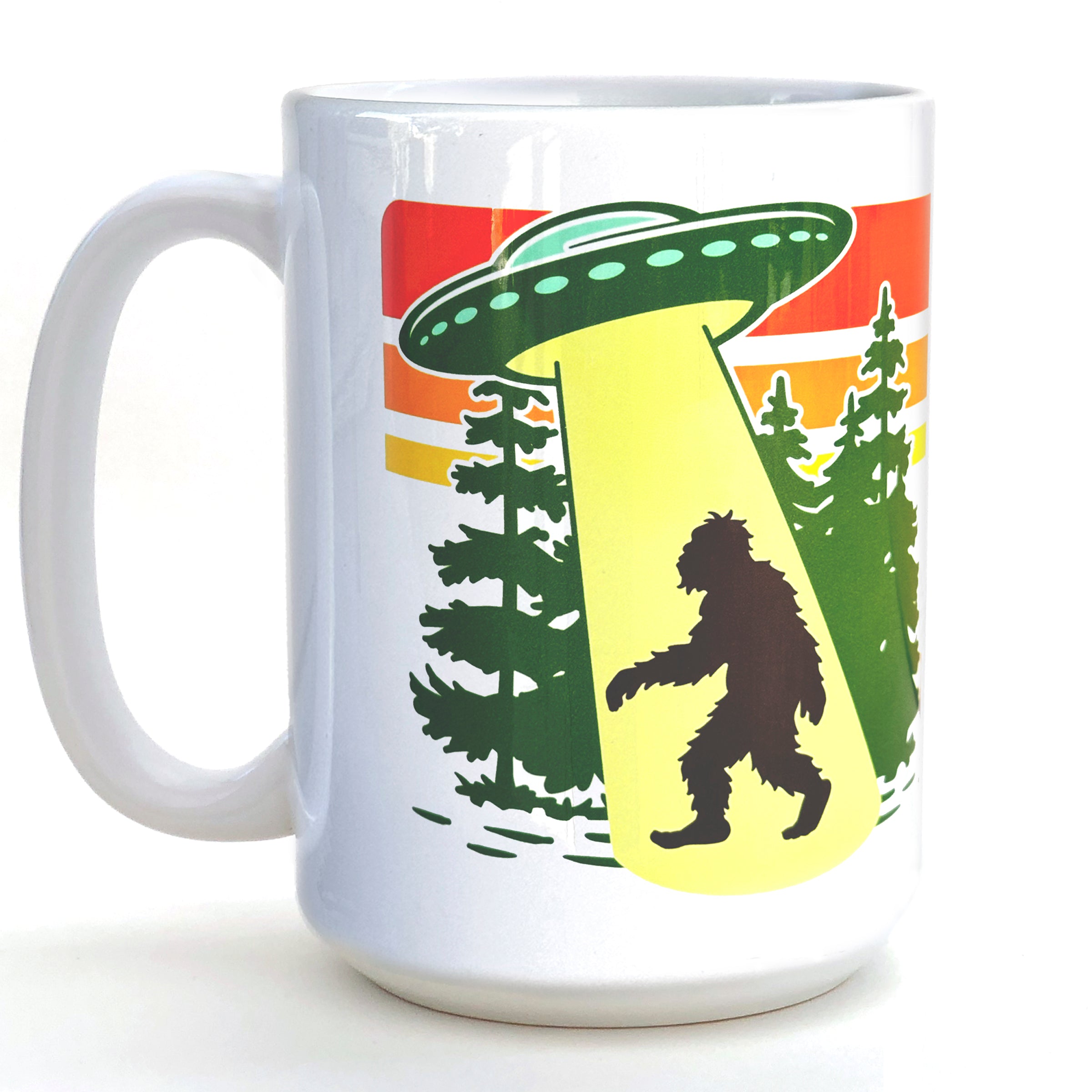 A white ceramic mug with a graphic design depicting a silhouetted figure walking through a forest, with a large green alien spacecraft hovering above.