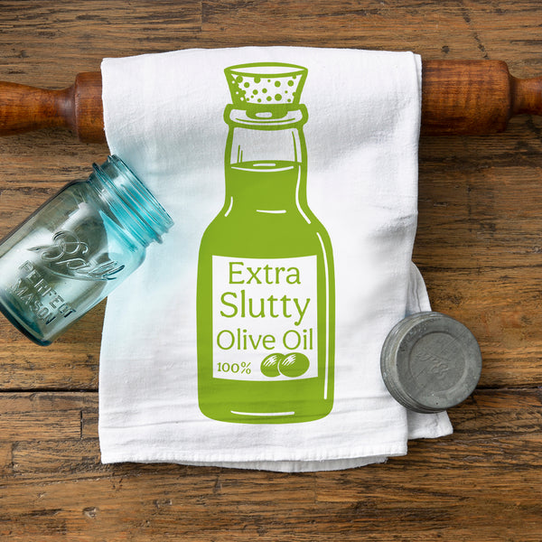Green Extra Slutty Olive Oil Cotton Tea Towel – Eco-Friendly, Screen Printed Kitchen Towel displayed with a vintage glass jar and circular metal container on a rustic wooden surface.