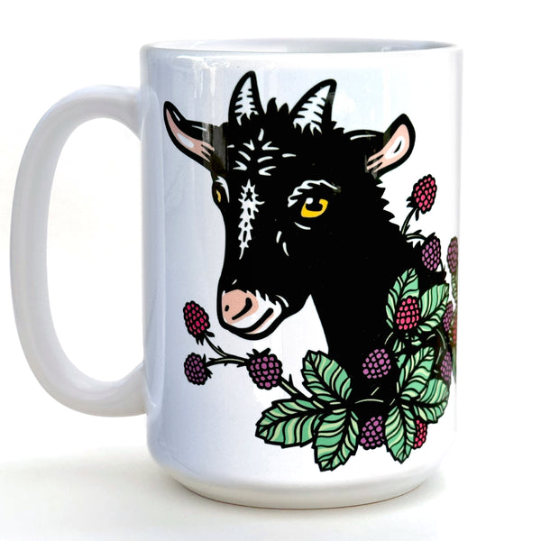 A white ceramic mug with a black goat illustration on it, surrounded by berries and leaves.