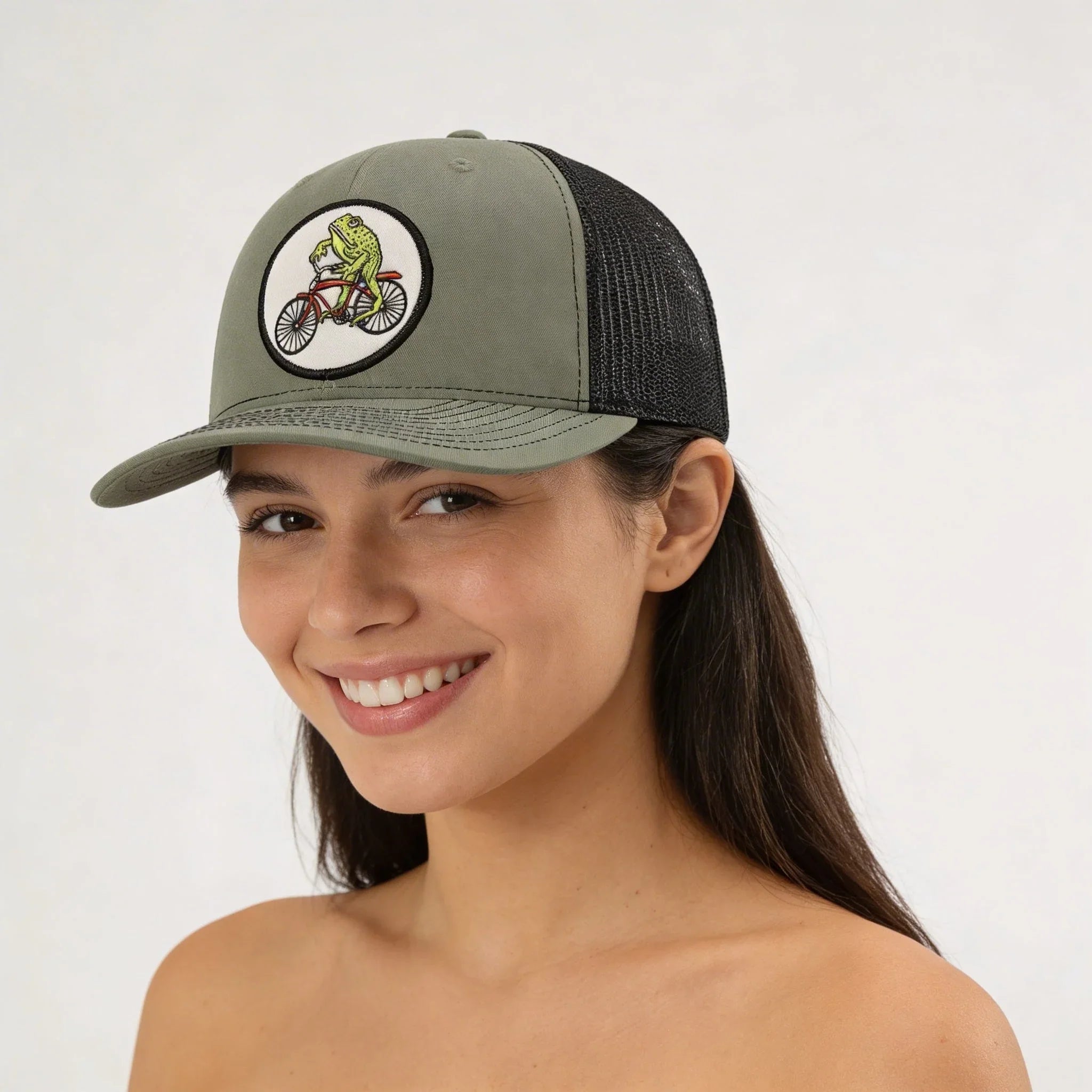 A woman wearing a green baseball cap with a cartoon image of a person riding a bicycle on it.