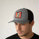 A man wearing a gray baseball cap with an orange and black graphic of a cartoon raccoon playing a guitar.