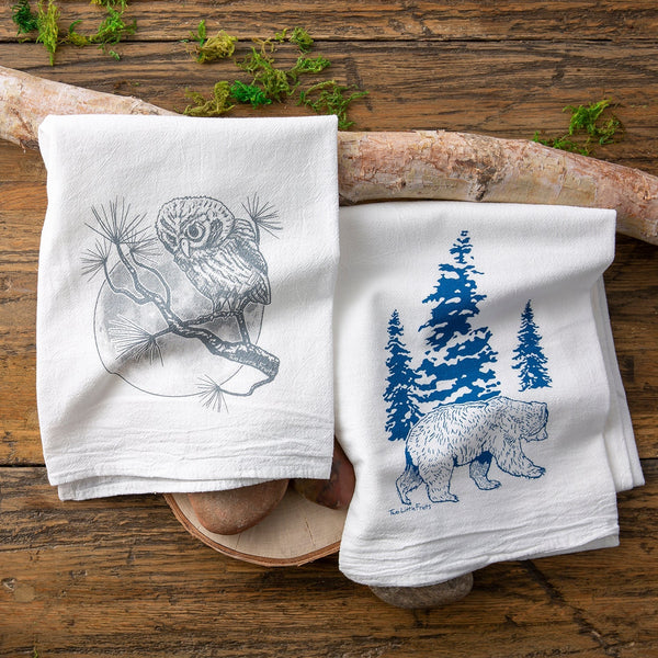 Owl and Bear Kitchen Towel Set featuring a grey owl perched on a branch and a blue bear amidst pine trees, part of a unique tea towel set by Two Little Fruits.