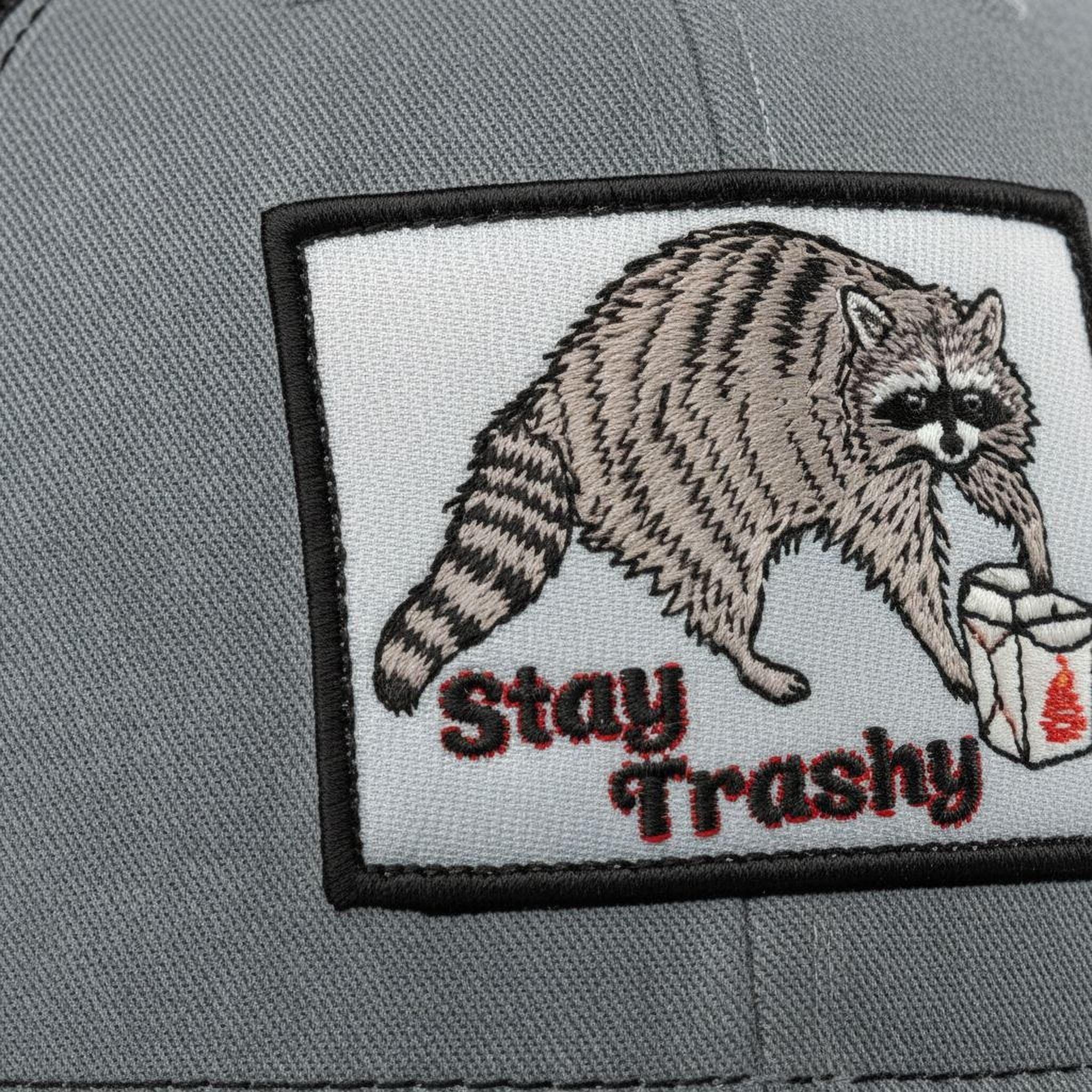 A gray fabric with a patch featuring a raccoon and the text "Stay Trashy" printed on it.