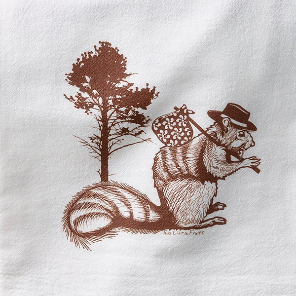A charming squirrel tea towel featuring a whimsical illustration of a squirrel wearing a hat, standing beside a tree, perfect for adding a touch of fun to your kitchen.