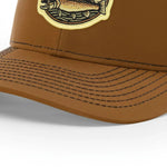 A close-up view of a brown baseball cap with a fish embroidered patch on the front.