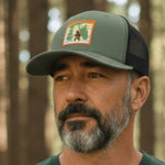Man wearing a green t-shirt and cap standing in a forest