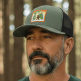Man wearing a green t-shirt and cap standing in a forest