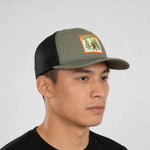 A man wearing a green baseball cap with a patch on it.