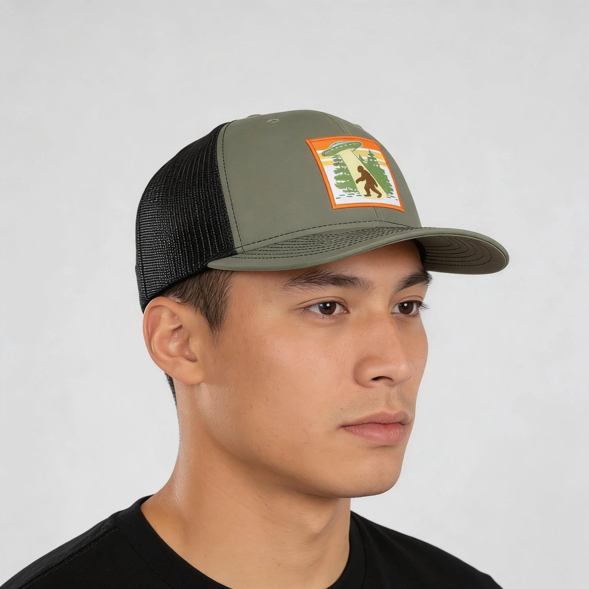 A man wearing a green baseball cap with a patch on it.