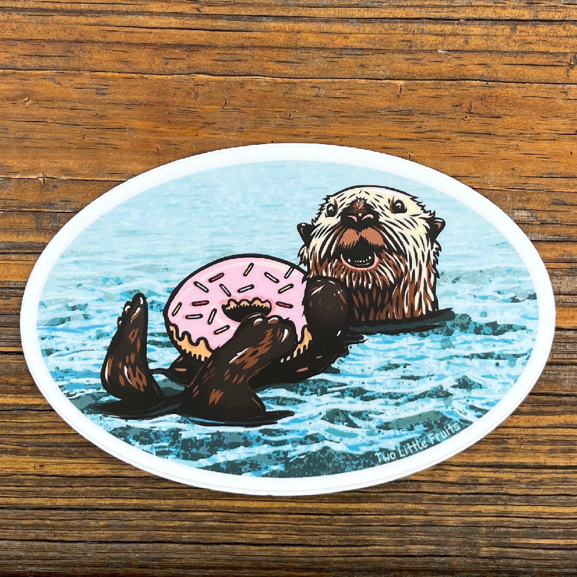 Cheerful Sea Otter Sticker featuring a cute otter holding a pink sprinkle doughnut floating in water.