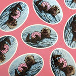 Colorful Sea Otter Stickers arranged on a pink background, showcasing the playful otter with a doughnut.