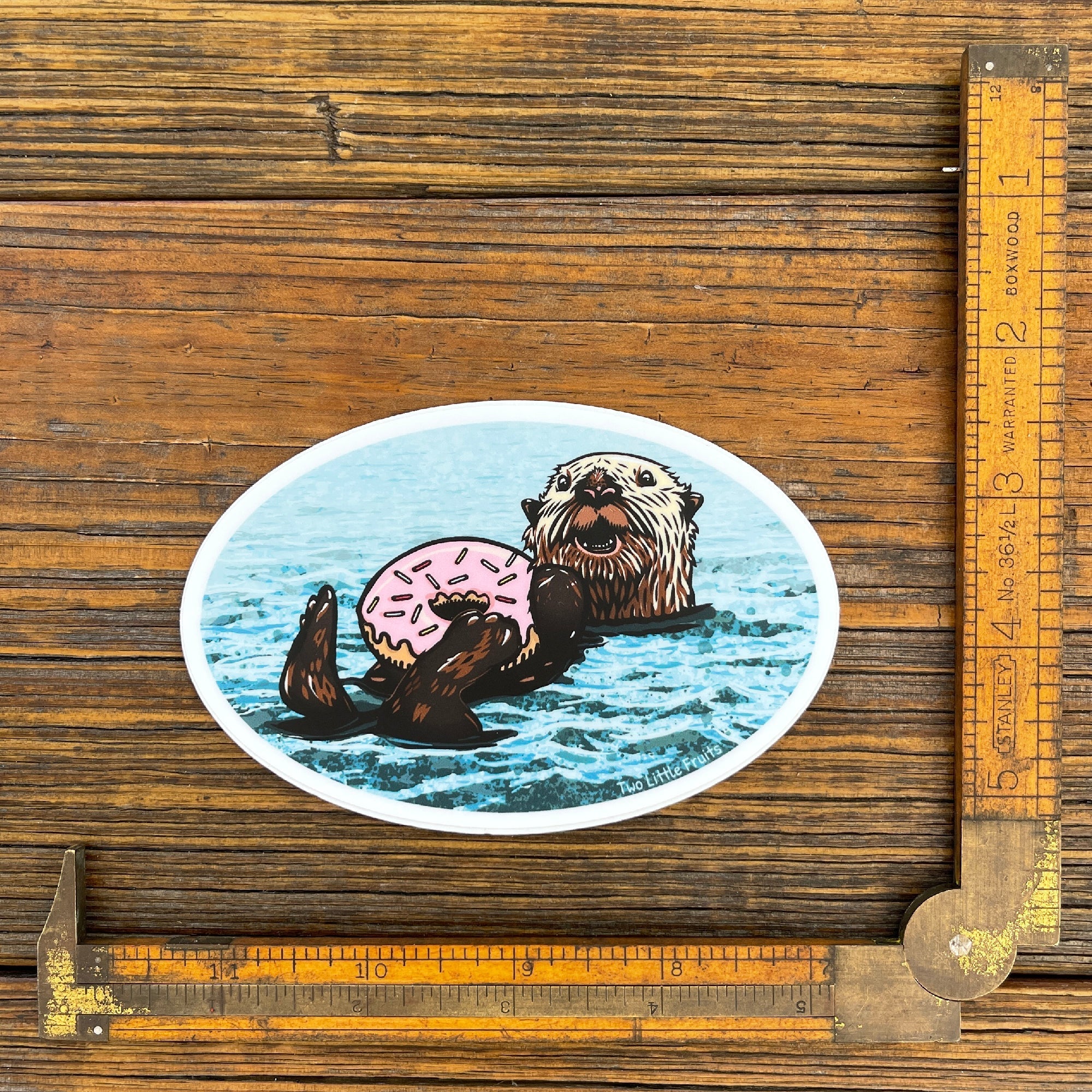 Measuring Sea Otter Sticker with a fun design of an otter enjoying a pink sprinkle doughnut in water.