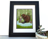 Framed beaver art print featuring a playful beaver by a stream with a vibrant green background, showcasing nature in a charming way.