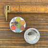 Bee button pin displayed next to a vintage ruler for size comparison, featuring a detailed illustration of a bee on a hexagonal background, measuring 1.25 inches.