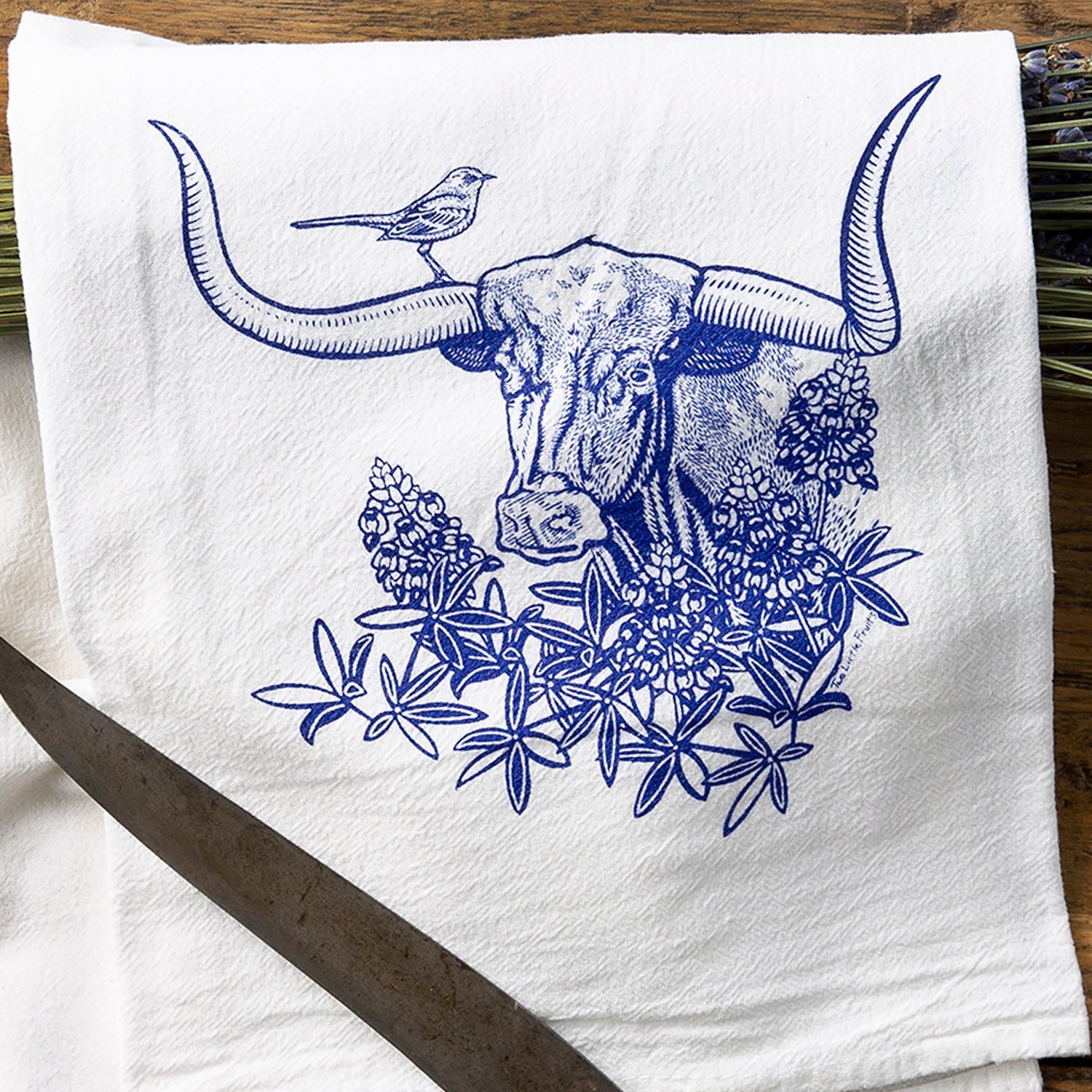 Close-up of a colorful tea towel set featuring a brown bison surrounded by sunflowers, with decorative items scattered around.