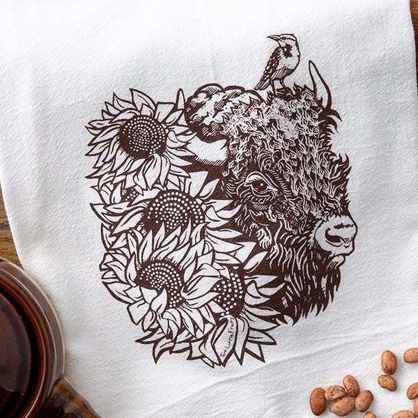 Elegant colorful tea towel featuring a blue longhorn steer decorated with flowers, presented with a tag on a white backdrop.