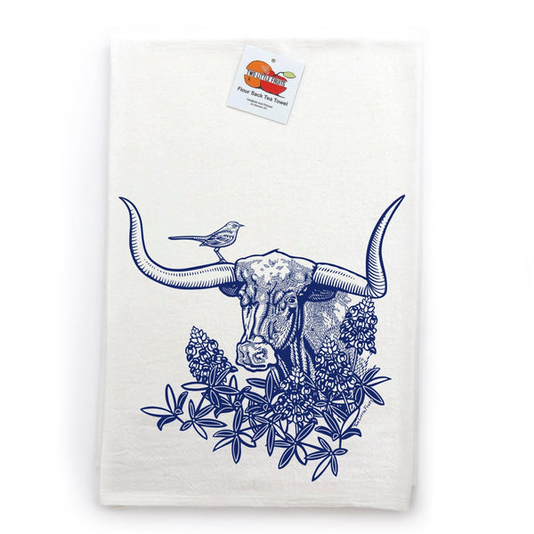 Vibrant blue longhorn steer colorful tea towel displayed with lavender and a knife on a wooden surface, emphasizing its artistic design.