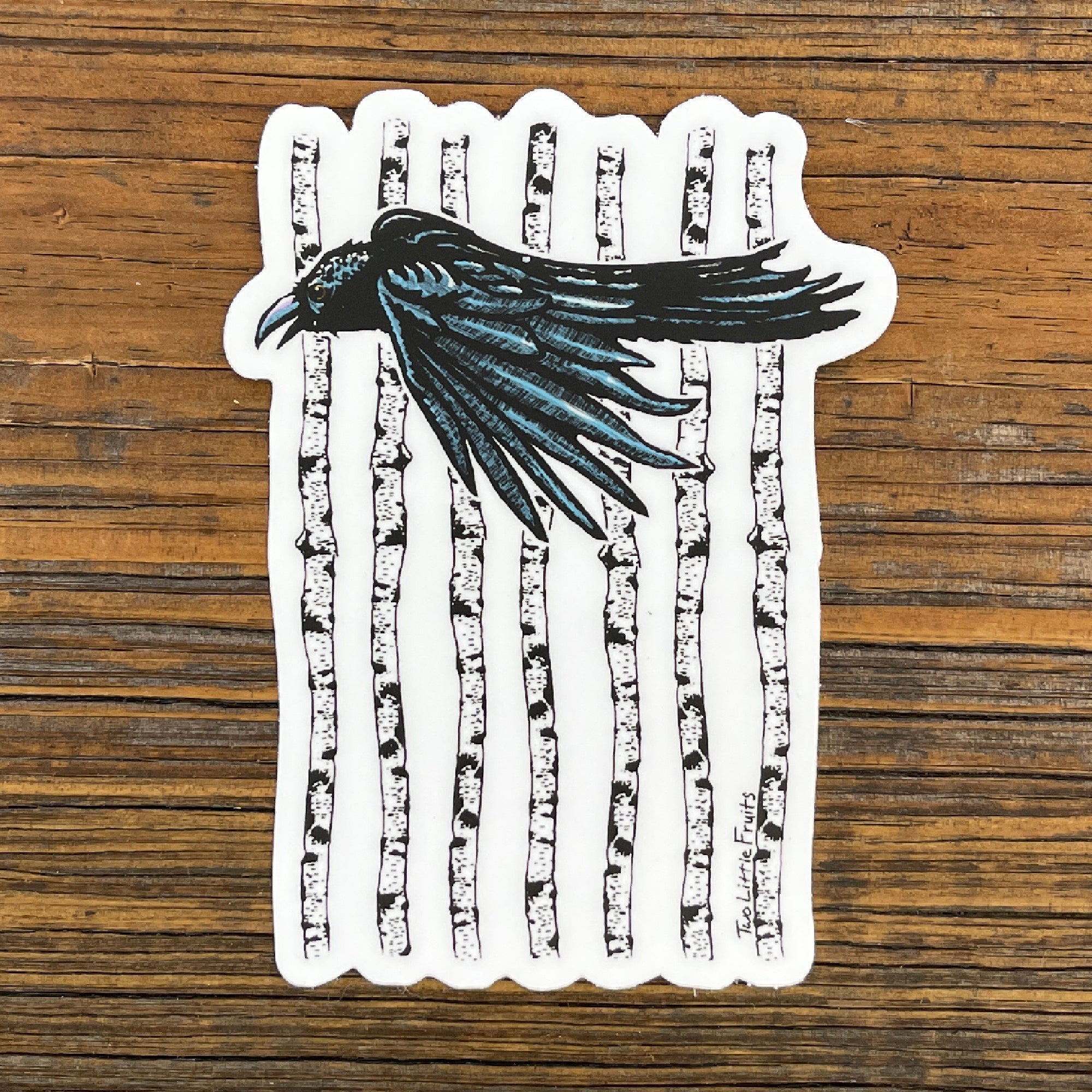 Black Crow Sticker with Aspen Forest Design - Durable Waterproof Vinyl Decal 3" x 4.03" against a wooden background, showcasing a crow in flight amidst white aspen trees.