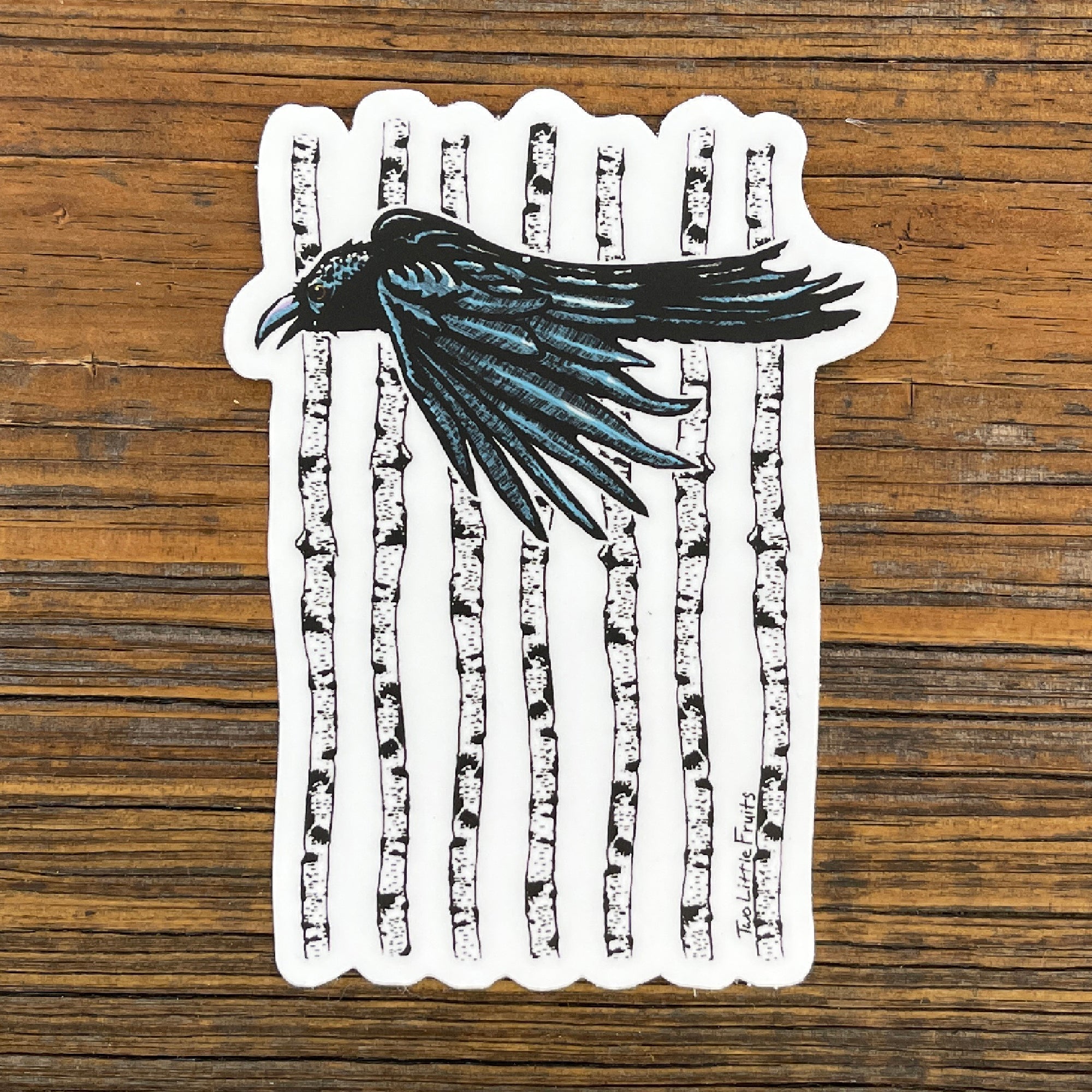 Black Crow Sticker with Aspen Forest Design - Durable Waterproof Vinyl Decal 3" x 4.03" against a wooden background, showcasing a crow in flight amidst white aspen trees.