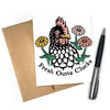A chicken greeting card featuring an illustrated chicken with flowers, labeled 'Fresh Outta Clucks', alongside a brown envelope and a pen.