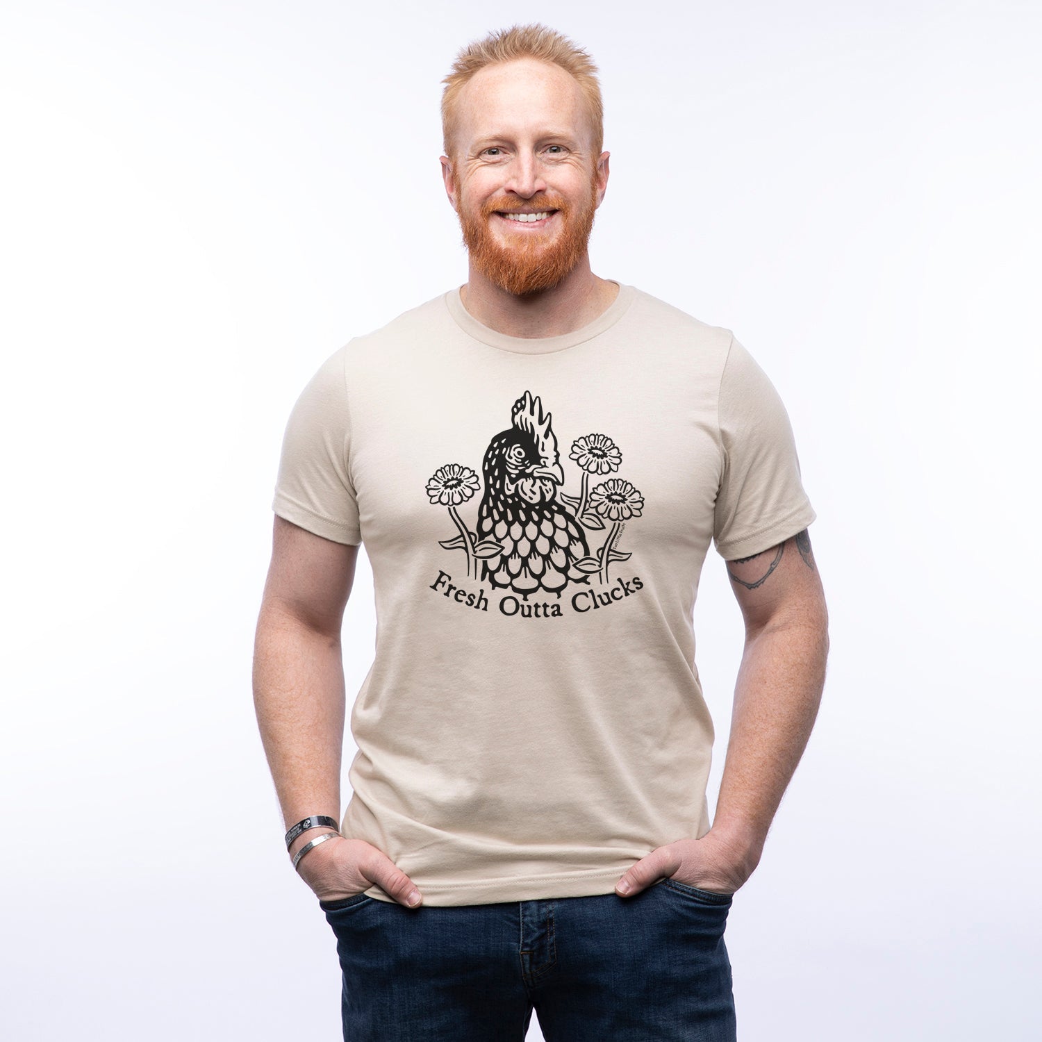 A smiling man wearing a beige funny chicken shirt, featuring the text 'Fresh Outta Clucks' and a playful chicken graphic. Perfect for casual wear or gifts for chicken lovers.