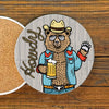 Cheerful Cowboy Drink Coaster featuring a bear in sunglasses and a cowboy hat, holding a beer, perfect for adding fun to your drinkware collection. Ideal cowboy ceramic coasters.