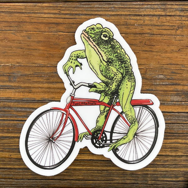 Close-up of a unique frog art sticker with a detailed drawing of a frog on a red bicycle, perfect for adding personality to your belongings.