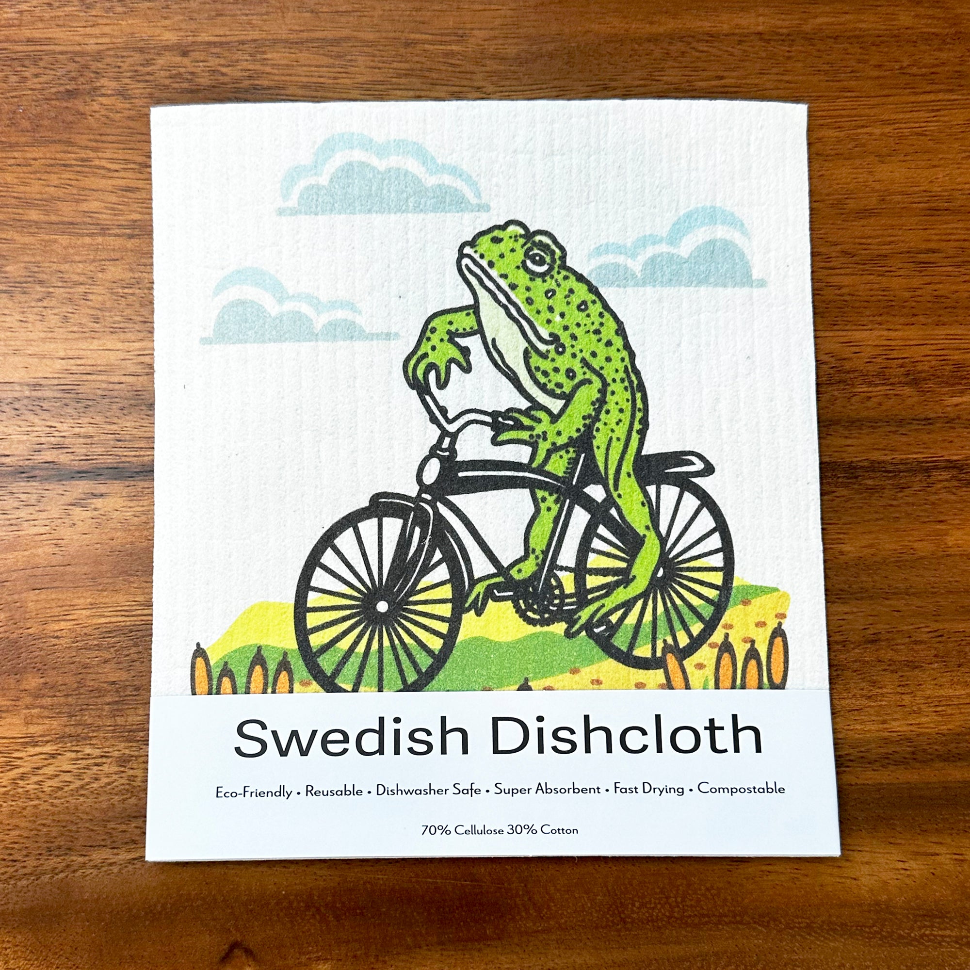 A vibrant Frog On A Bike Swedish Dishcloth lying flat, highlighting its eco-friendly materials and functionality as a compostable kitchen cloth.