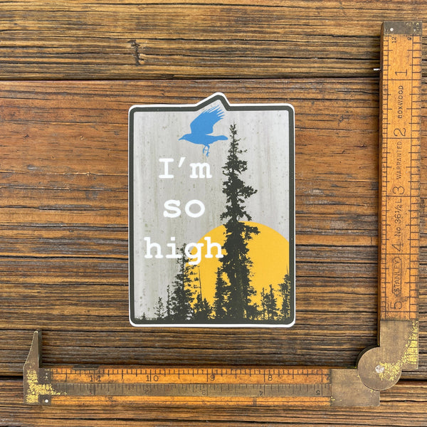 Funny cannabis sticker placed next to a ruler for size reference, showcasing the design of a raven flying with 'I'm So High' text and a forest background.