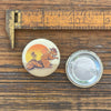 A Hobo Squirrel Button Pin featuring a whimsical illustration of a squirrel wearing a hat and carrying a bag, set against a sunset background, emphasizing Colorado pride.