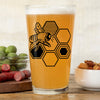 Enjoy your drinks in this stylish bee beer glass, featuring a vibrant bee and honeycomb design with a background of snacks.
