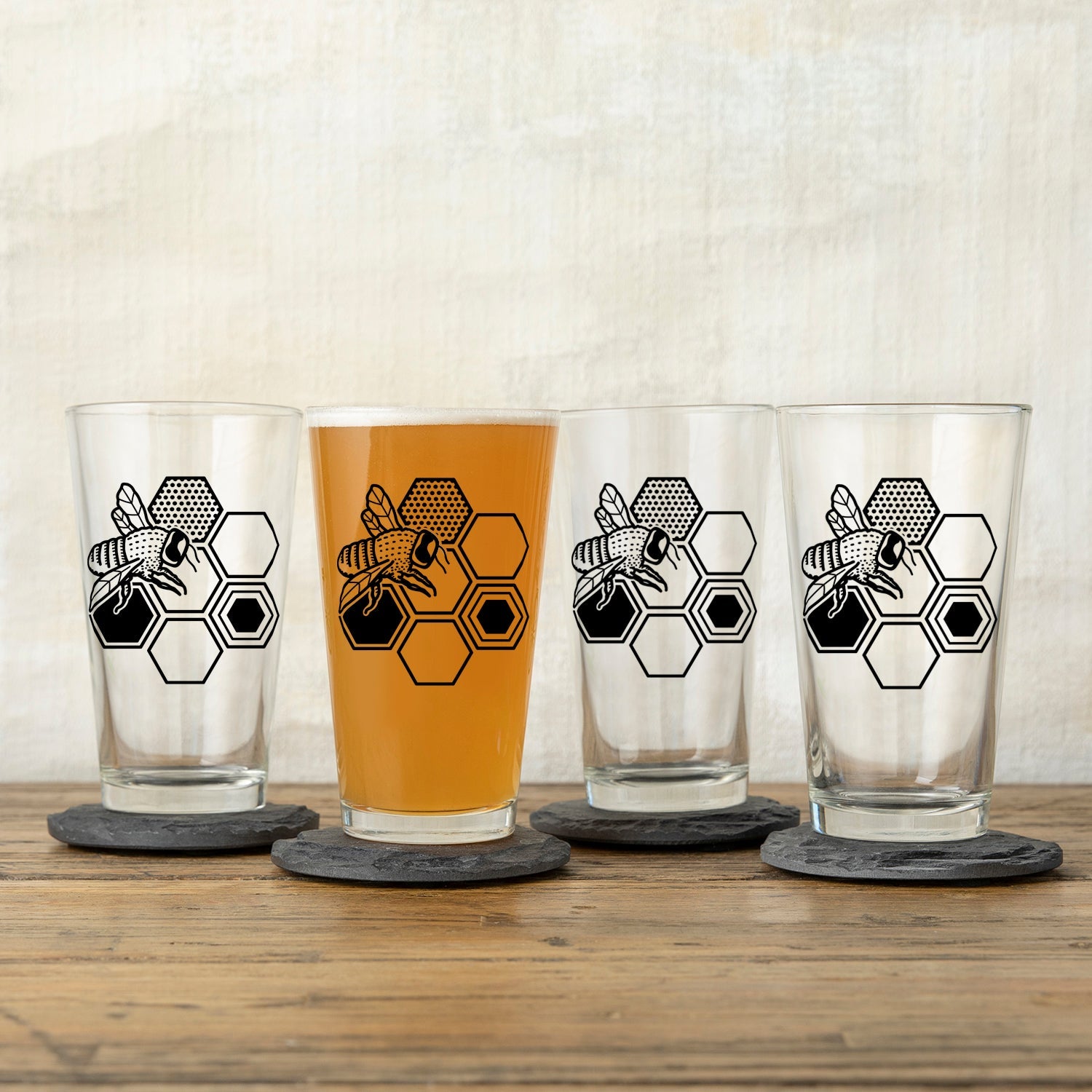 A collection of bee beer glasses displaying unique designs, perfect for serving drinks at gatherings.