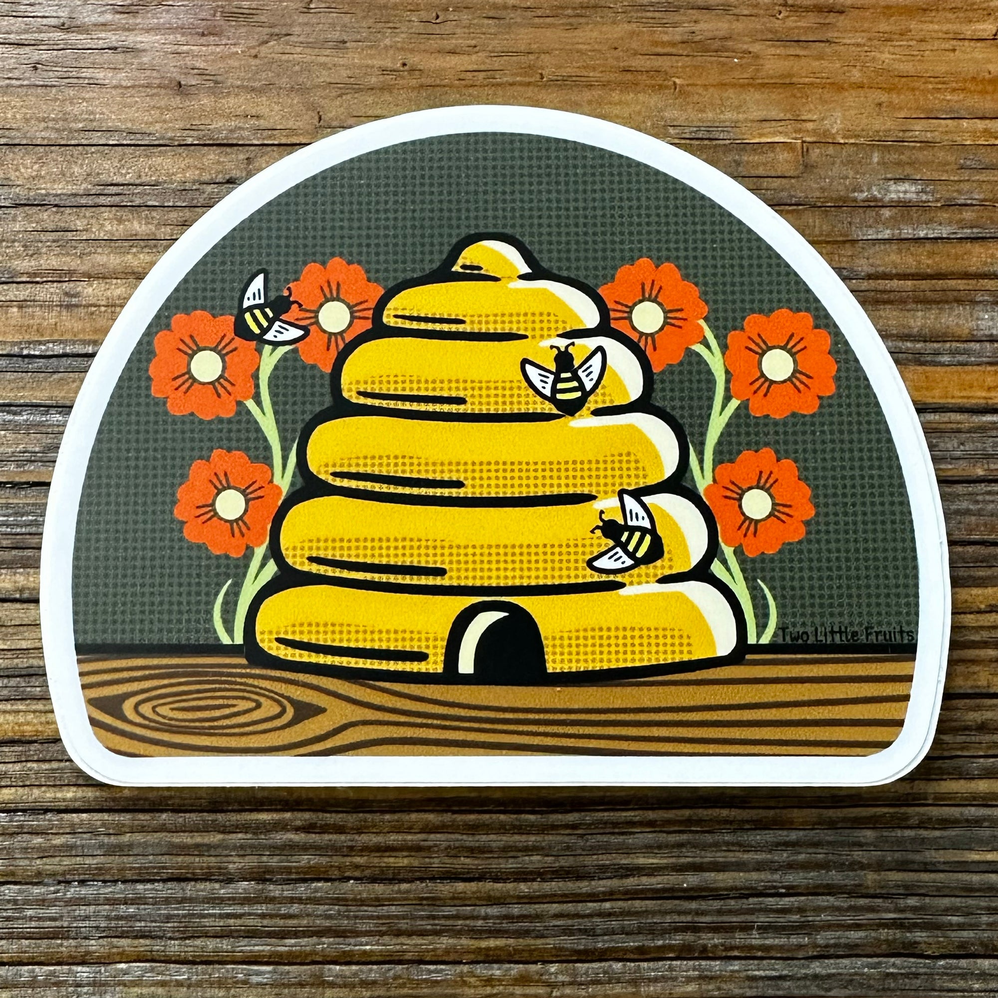 Adorable beehive die cut sticker featuring a skep beehive surrounded by colorful flowers and bees, perfect for personalizing your belongings.