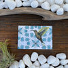Hummingbird Fridge Magnet beautifully displayed among natural stones, showcasing its vibrant design and artistic appeal.